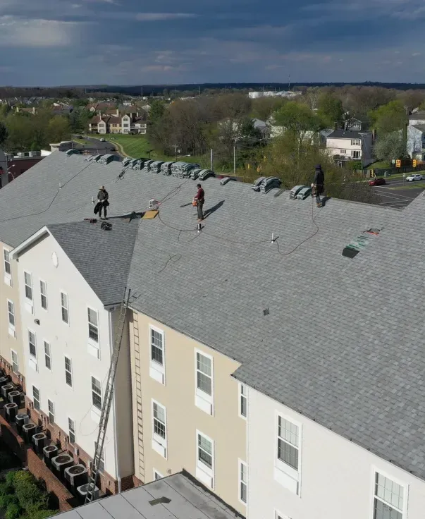 Workers installing a new roof on a multi-story building.